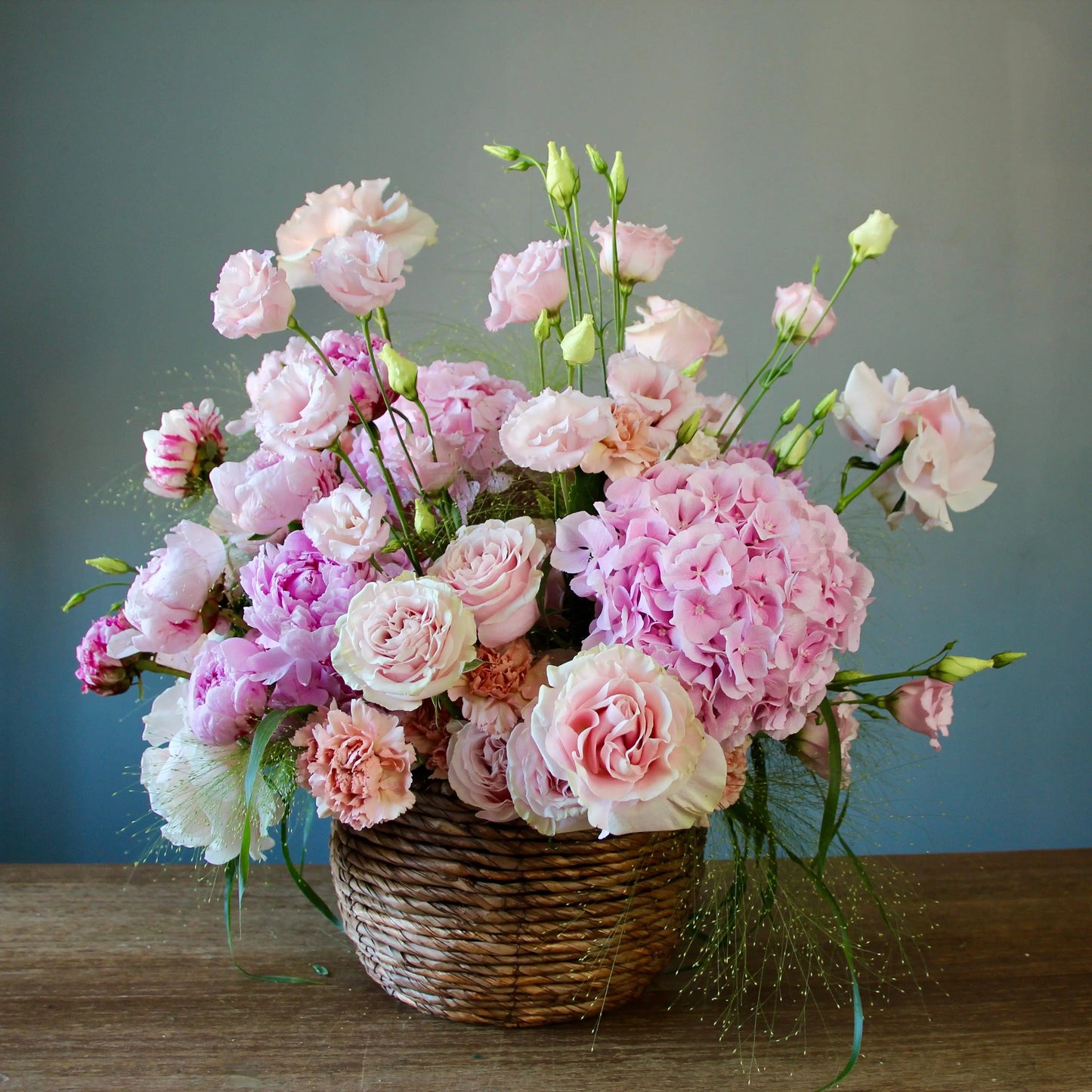 bouquet of pink peonies and greenery in a basket