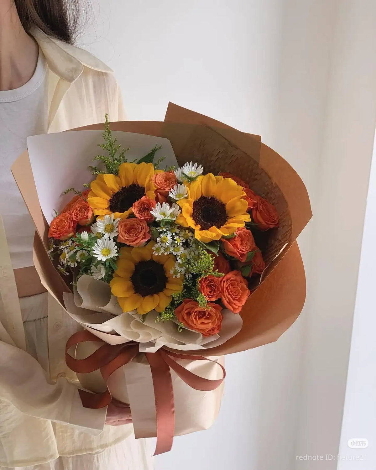 3 sunflowers and deep pink roses with small white flowers and greenery