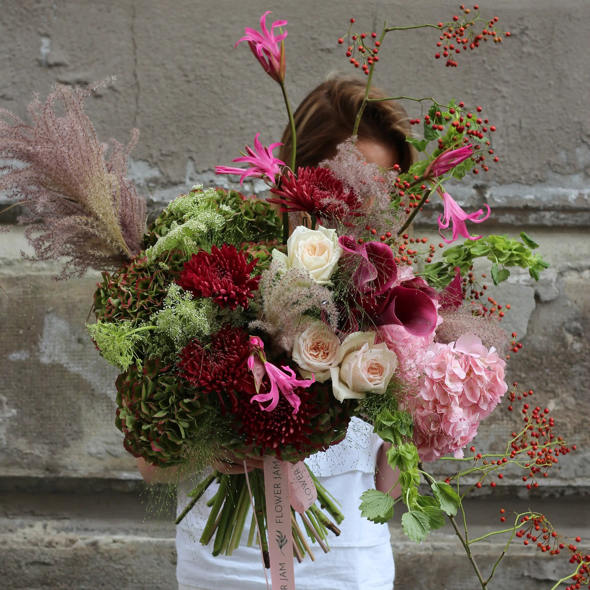 A blend of green and pink hydrangeas adorned with dark pink gerberas, pink callas and whte roses