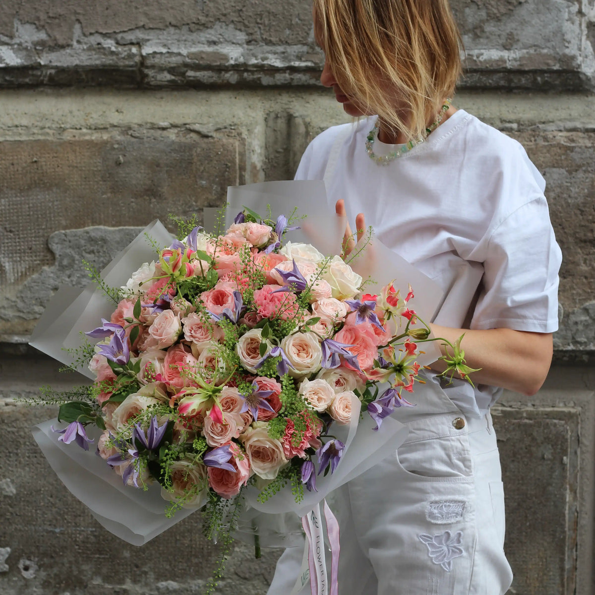 Woman holding a bouquet of pink, white and spray roses, dianthus, climatis and goodies.