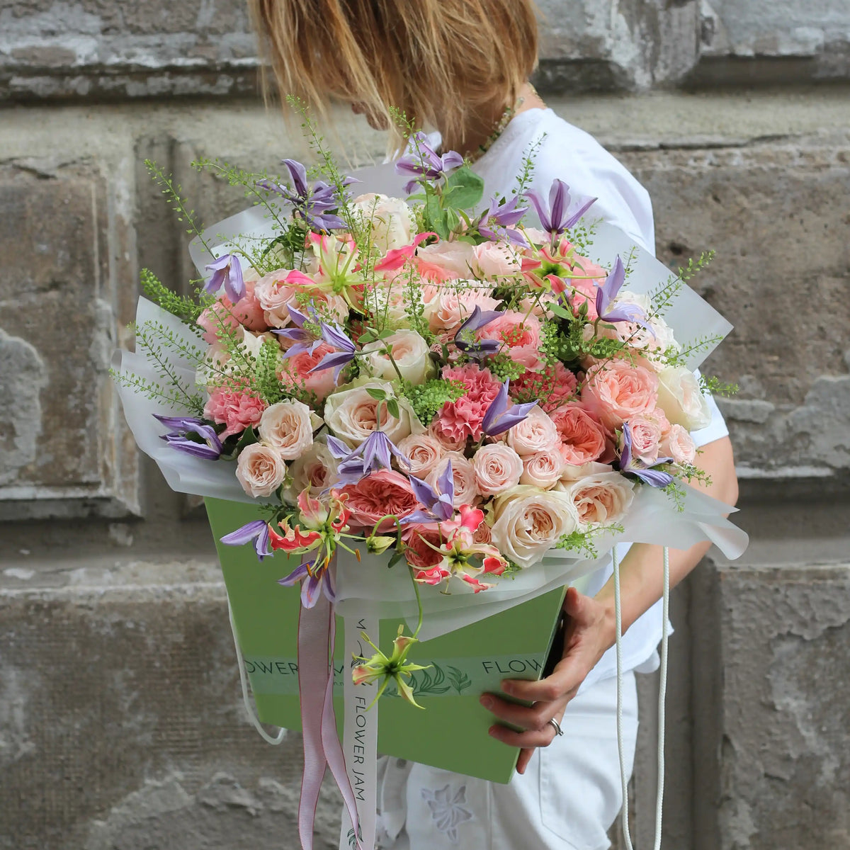 A bouquet of pink, white and purple flowers inside a green transportation box