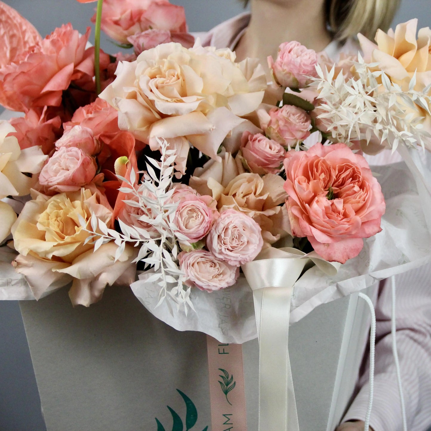 a bouquet of yellow, pink and peach roses in a box