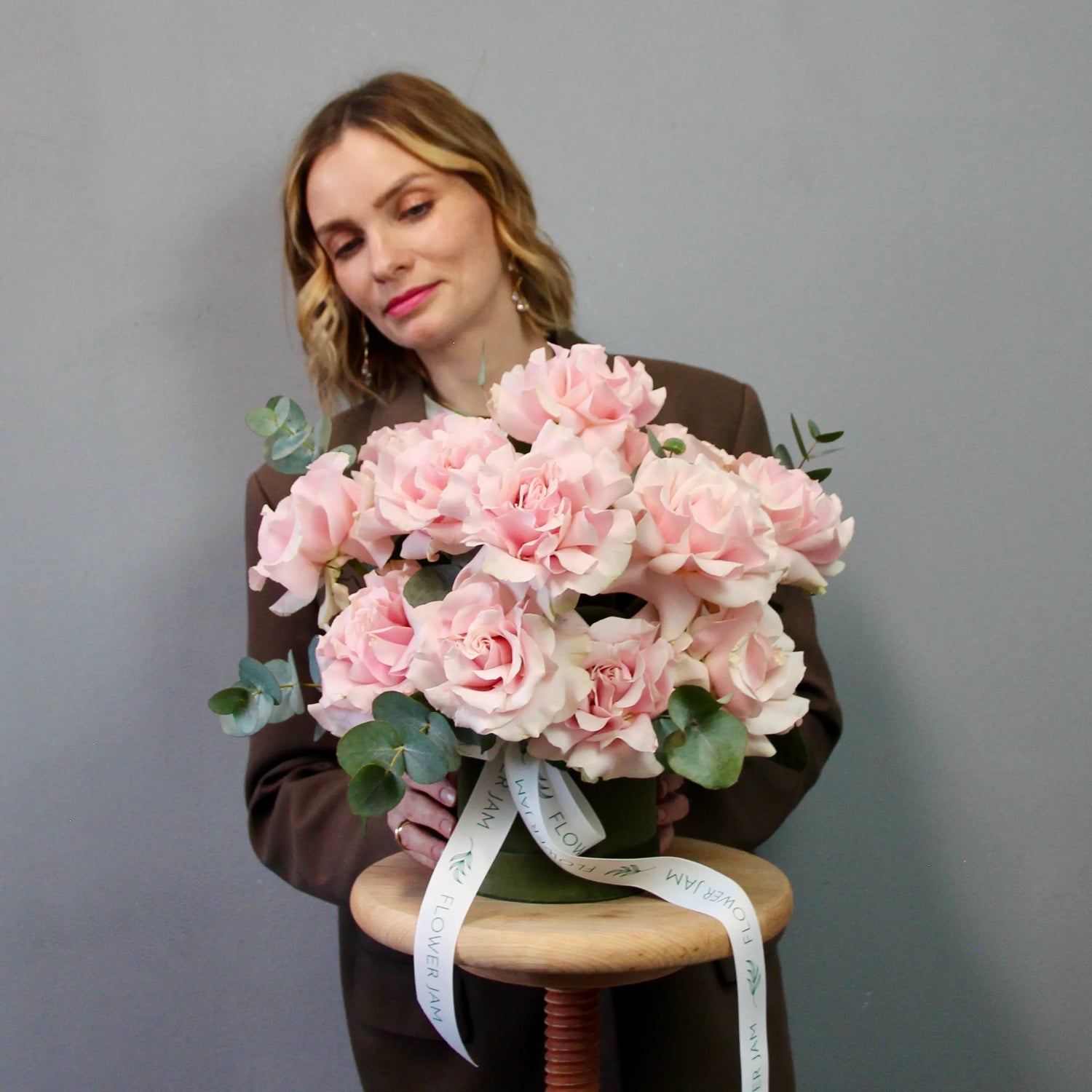 Woman holding a bouquet of pink flowers on a gray background