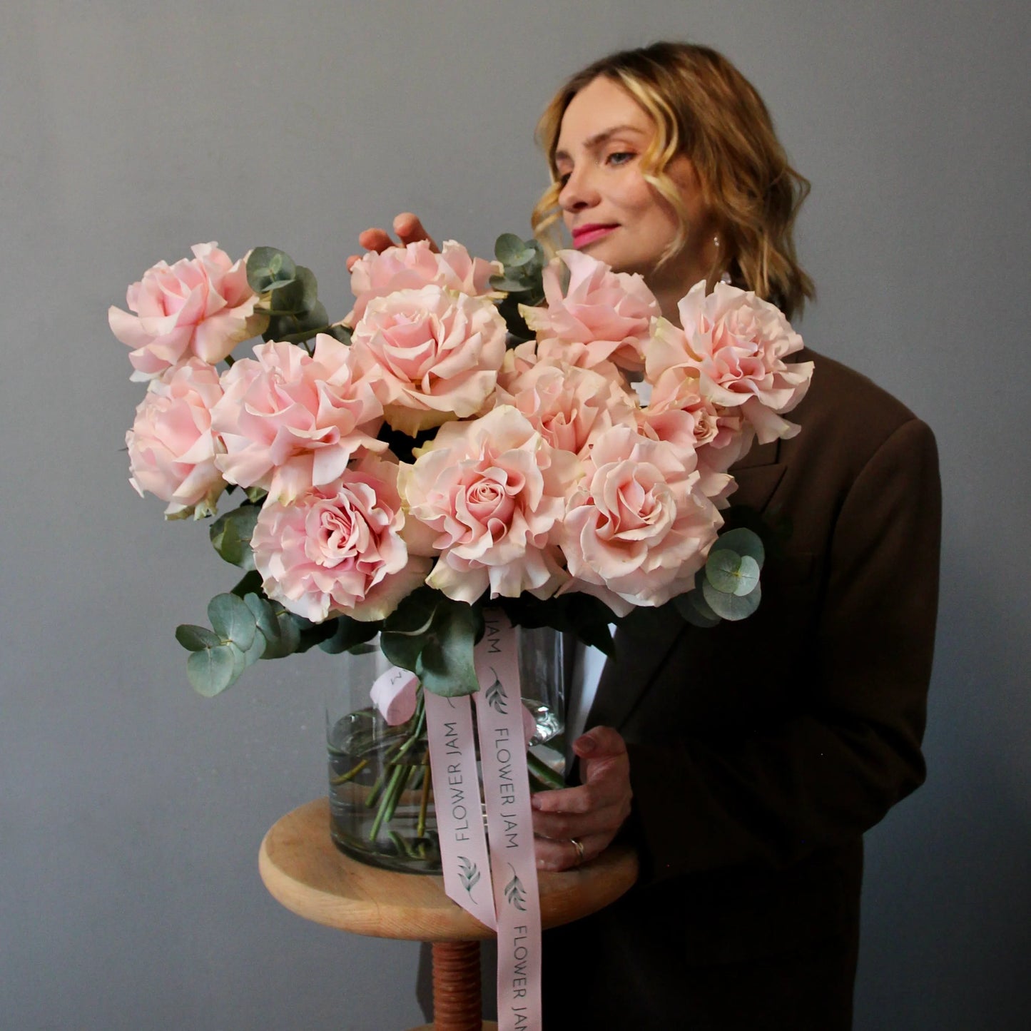 Woman holding a bouquet of pink flowers with a gray background
