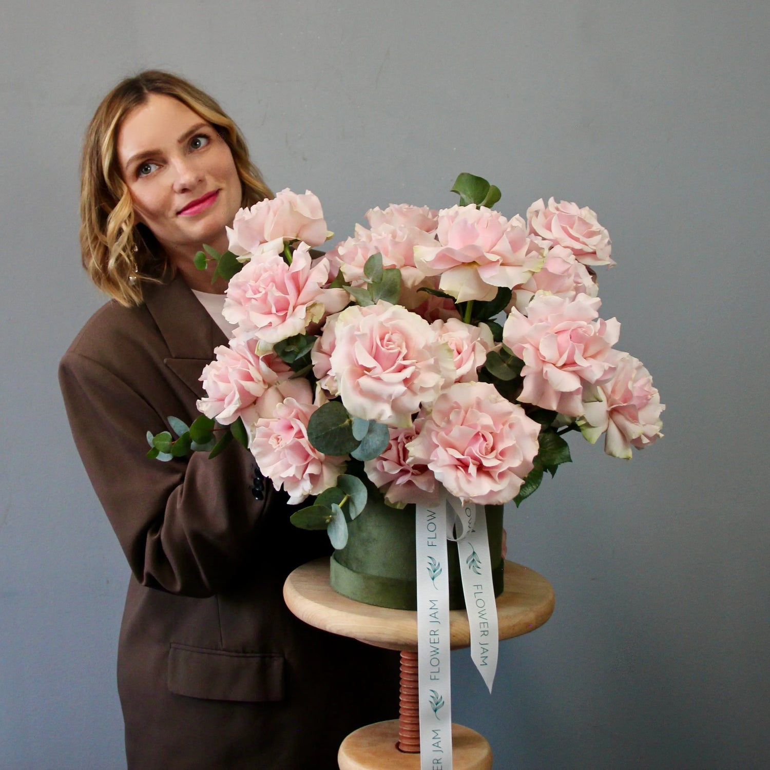 Woman holding a bouquet of pink flowers on a gray background